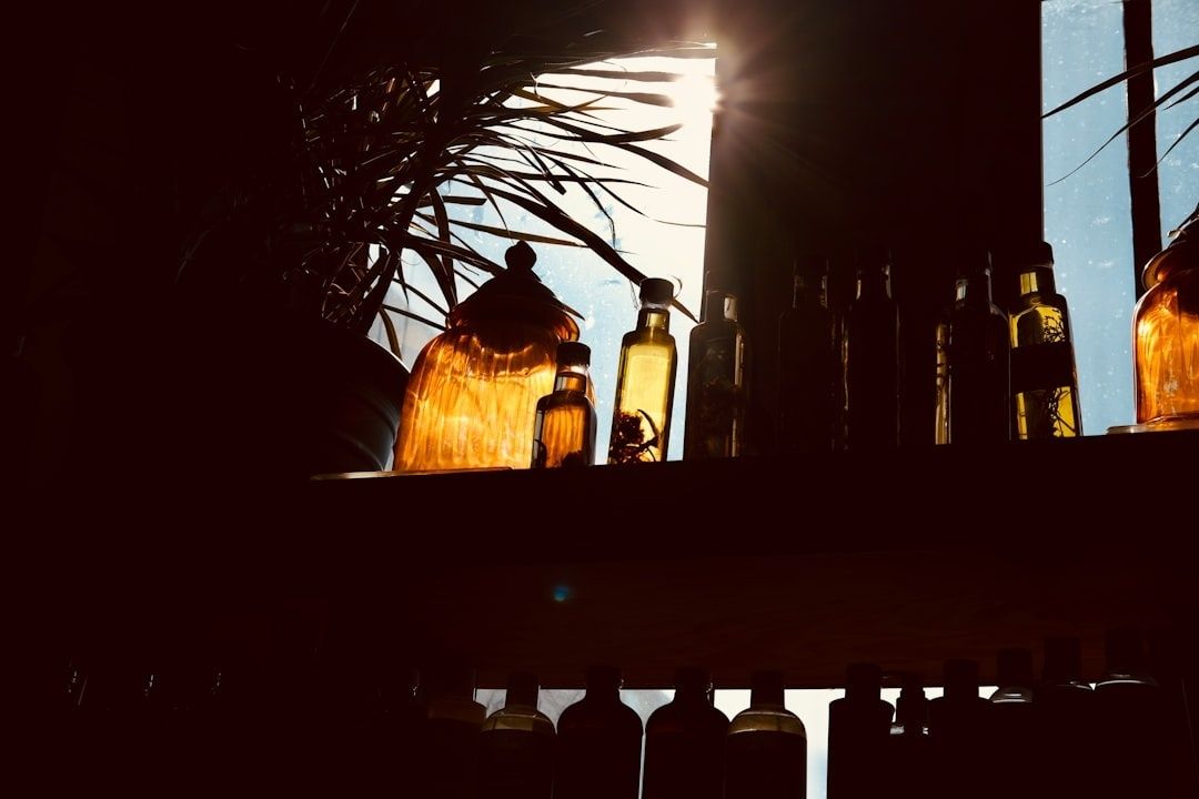 Bouteilles d’huiles végétales ambrées, placées devant une fenêtre lumineuse