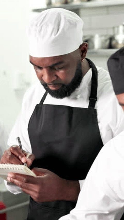 Chef prenant des notes dans un carnet en cuisine professionnelle